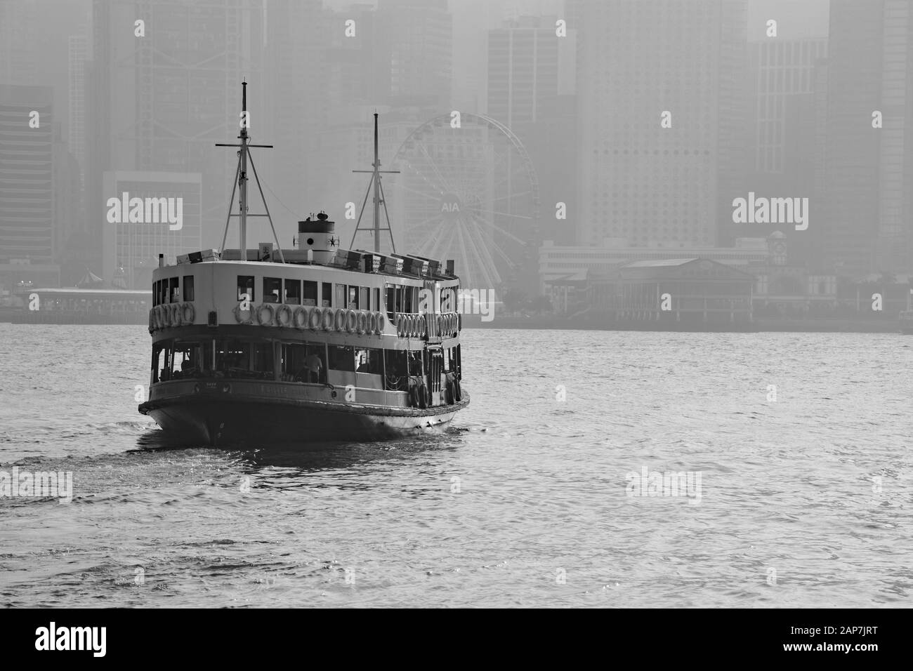 Schwarz-Weiß-Bild der Kreuzung der Star Ferry zwischen Central District und Kowloon Peninsula mit einem Smog, der über der Innenstadt von Hongkong hängt. Stockfoto