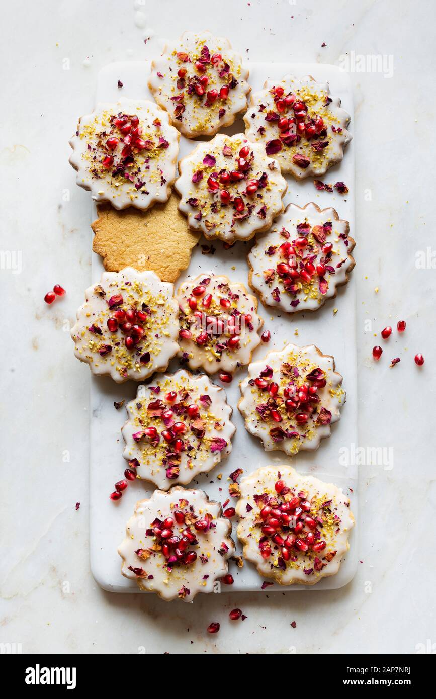 Glutenfreie Sugar Cookies mit eggless Glasur mit Granatapfel Samen eingerichtet, Rosenblätter und Pistazien Stockfoto