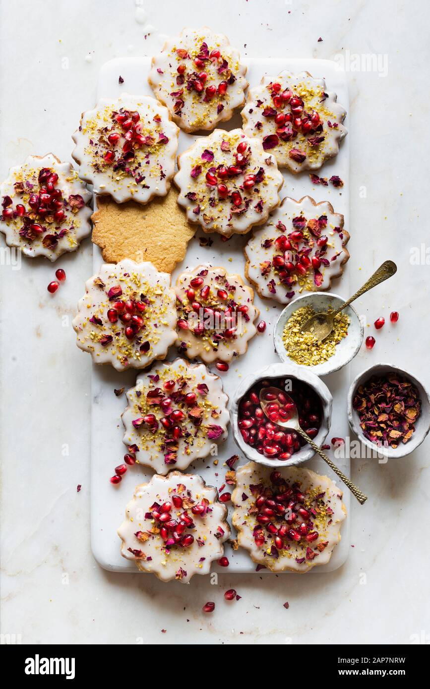 Glutenfreie Sugar Cookies mit eggless Glasur mit Granatapfel Samen eingerichtet, Rosenblätter und Pistazien Stockfoto