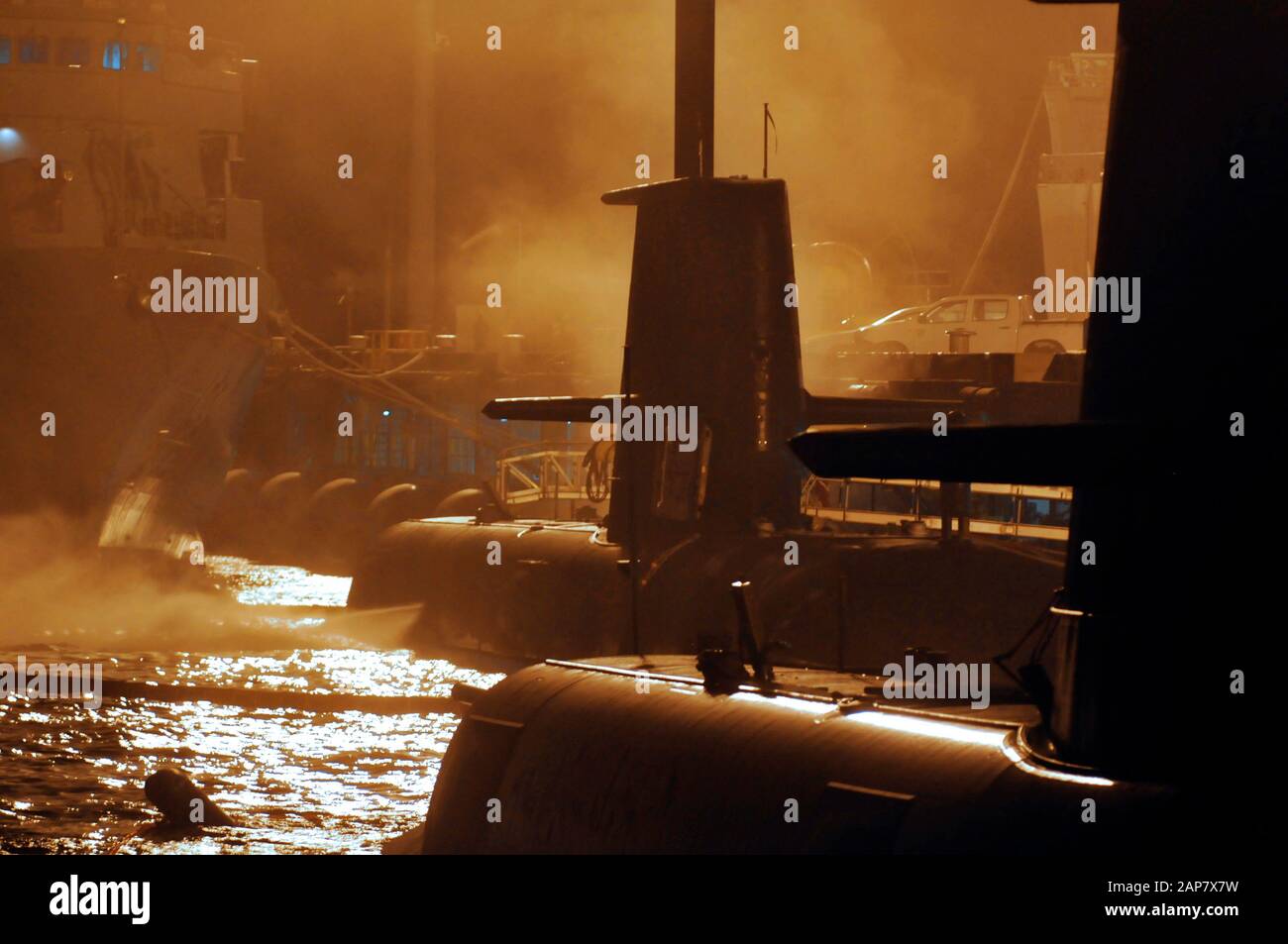 Morgennebel und Dampf umschließen zwei Silhouetten-Unterseeboote der Collins Klasse, die an die Wharf gebunden sind. Stockfoto