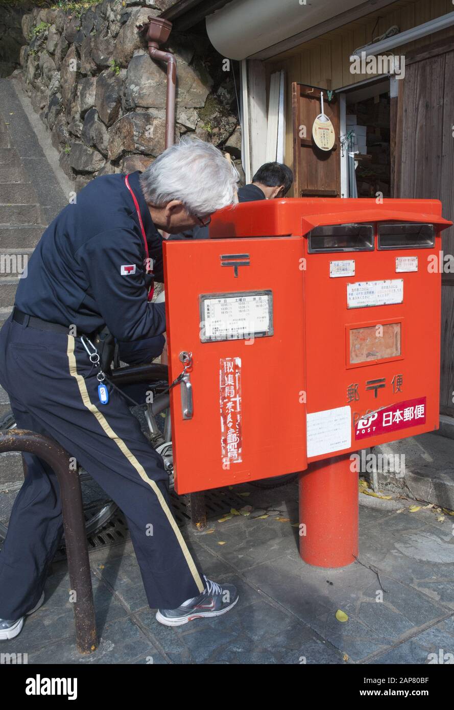 Japan Post Mailman (Postbote), der Post von einem Straßenpfeilerkasten in Nara sammelt Stockfoto