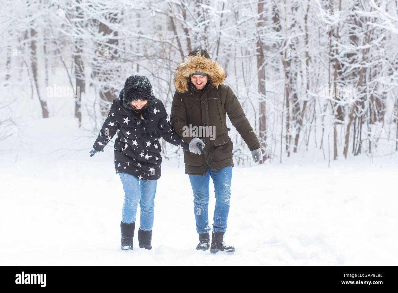 Junge Paare, die in einem verschneiten Park spazieren gehen. Wintersaison Stockfoto