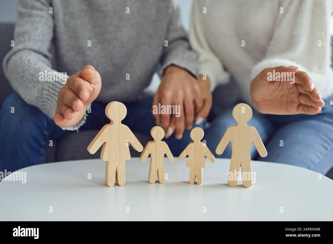 In den Händen einer Frau befindet sich eine Familie von Holzfiguren. Familienplanung Schutzkonzept Stockfoto