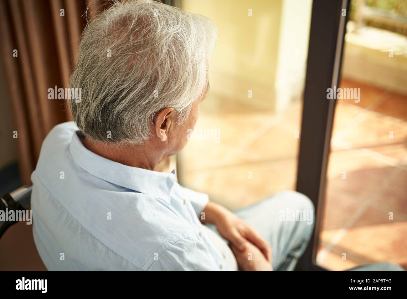 Hochwinkeliger Rückblick auf einen einsamen asiatischen alten Mann, der im Pflegeheim auf dem Rollstuhl sitzt Stockfoto