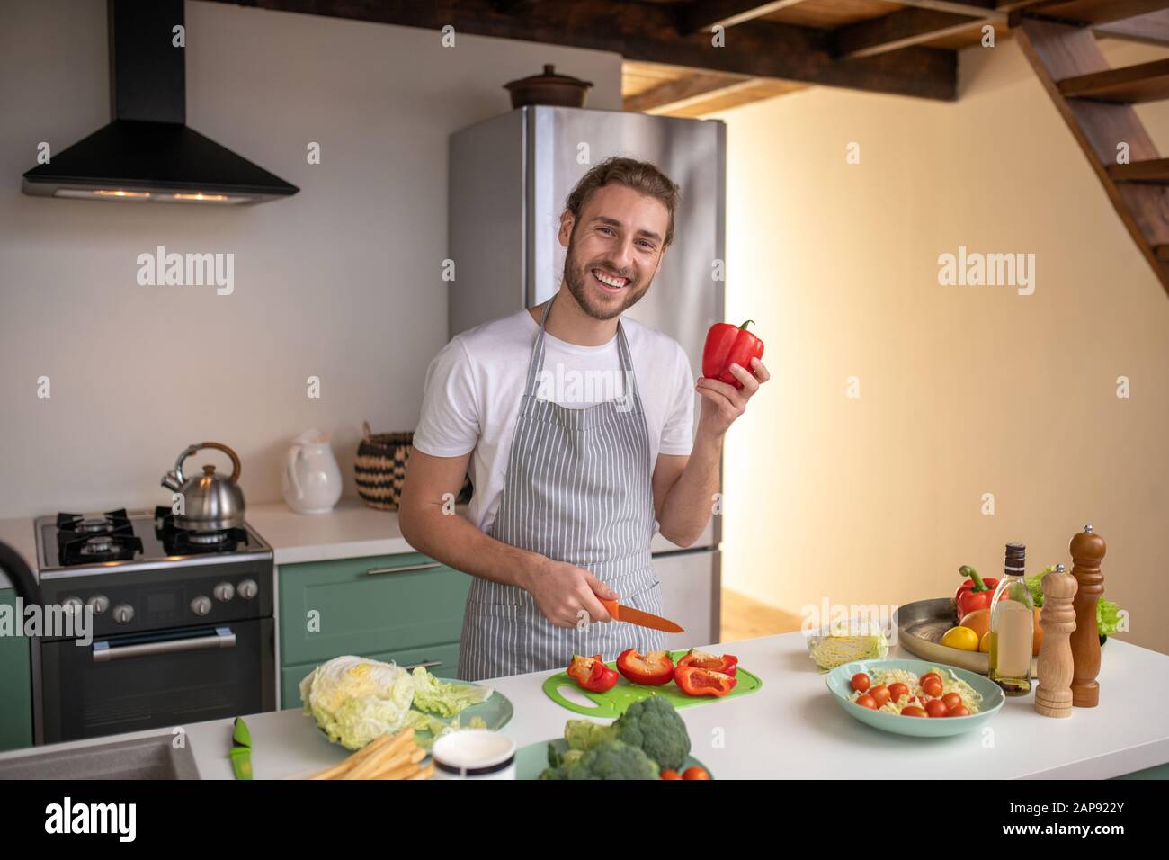 Lächelnder Koch, der ein neues Gericht mit Pfeffer zubereitet Stockfoto