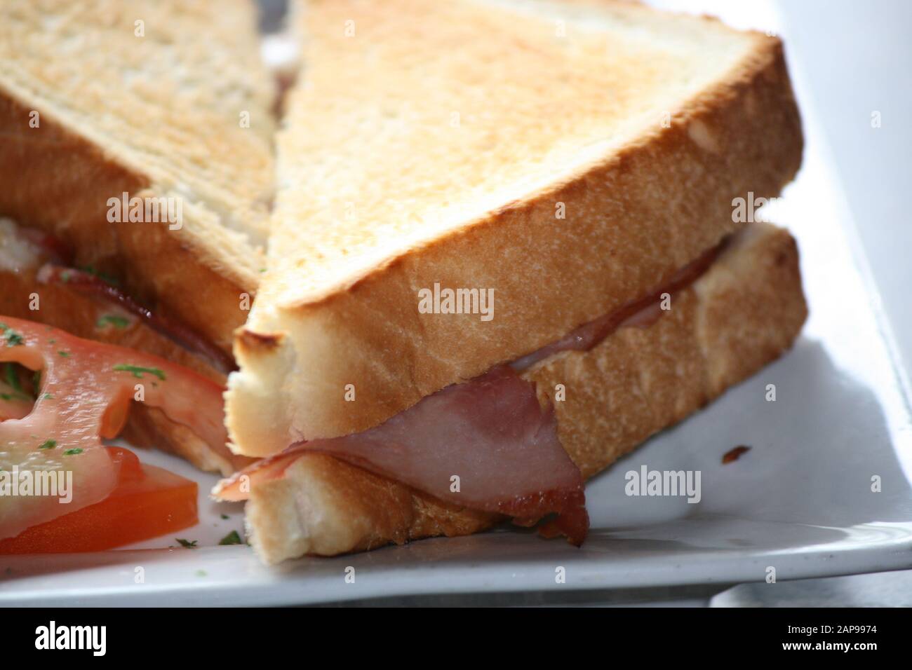 Gegrilltes Käsesandwich mit Speck und Tomaten zum Frühstück zum Mittag- oder Abendessen in einem Restaurant. Köstliche Speisen für einen Snack oder eine Mahlzeit Stockfoto