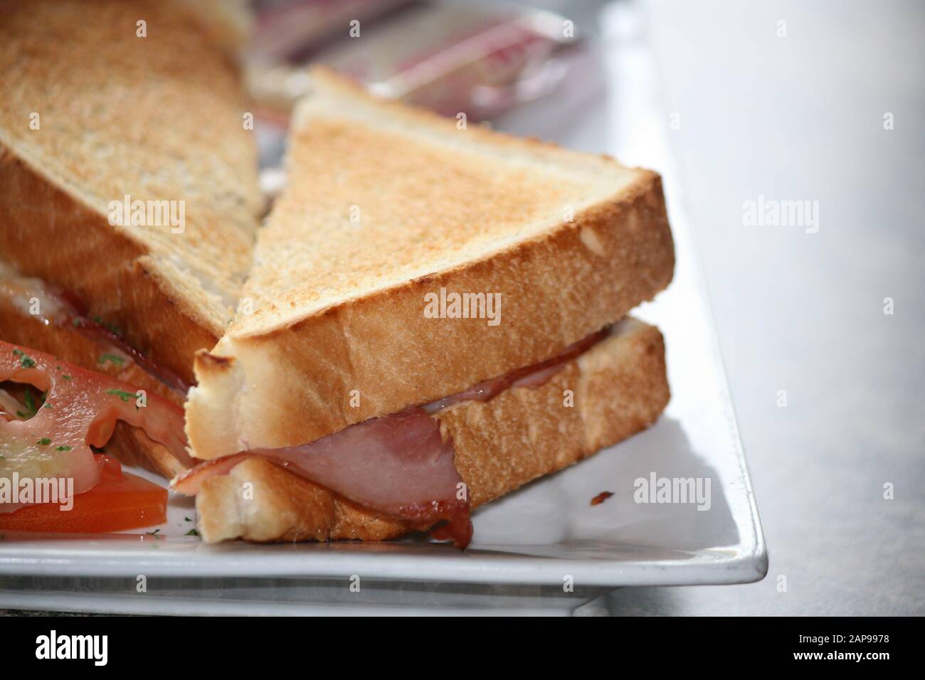 Gegrilltes Käsesandwich mit Speck und Tomaten zum Frühstück zum Mittag- oder Abendessen in einem Restaurant. Köstliche Speisen für einen Snack oder eine Mahlzeit Stockfoto