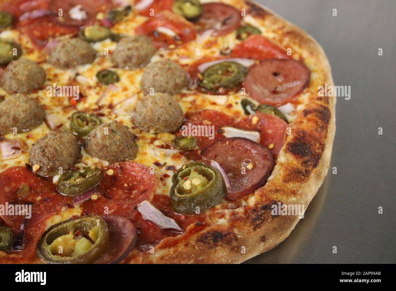 Frisch gebackene italienische Pizza, Pfefferoni, Pilze, Wursttopflecken, Pizzasauce, Mozzarella-Käse, Mitnahme oder Pizza-Lieferung im Pizza-Restaurant Stockfoto