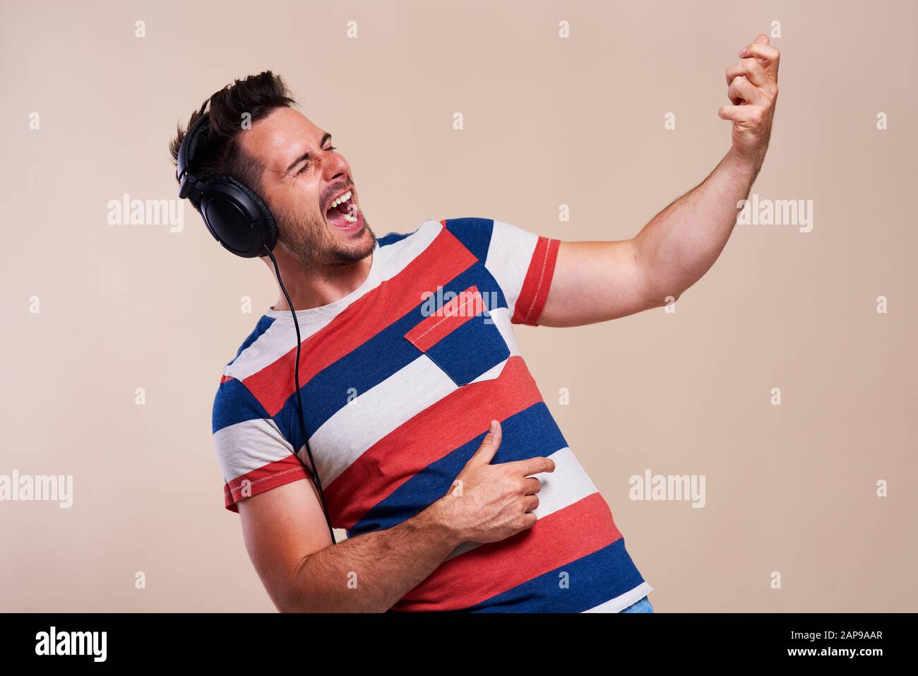 Verspielter Mann, der Musik hört und Gitarre spielt Stockfoto