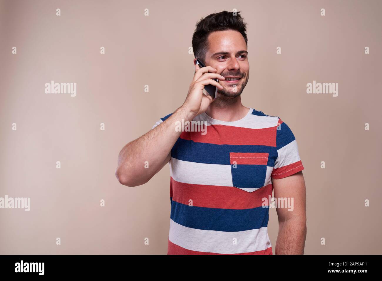 Lächelnd ist der junge Mann am Telefon Stockfoto