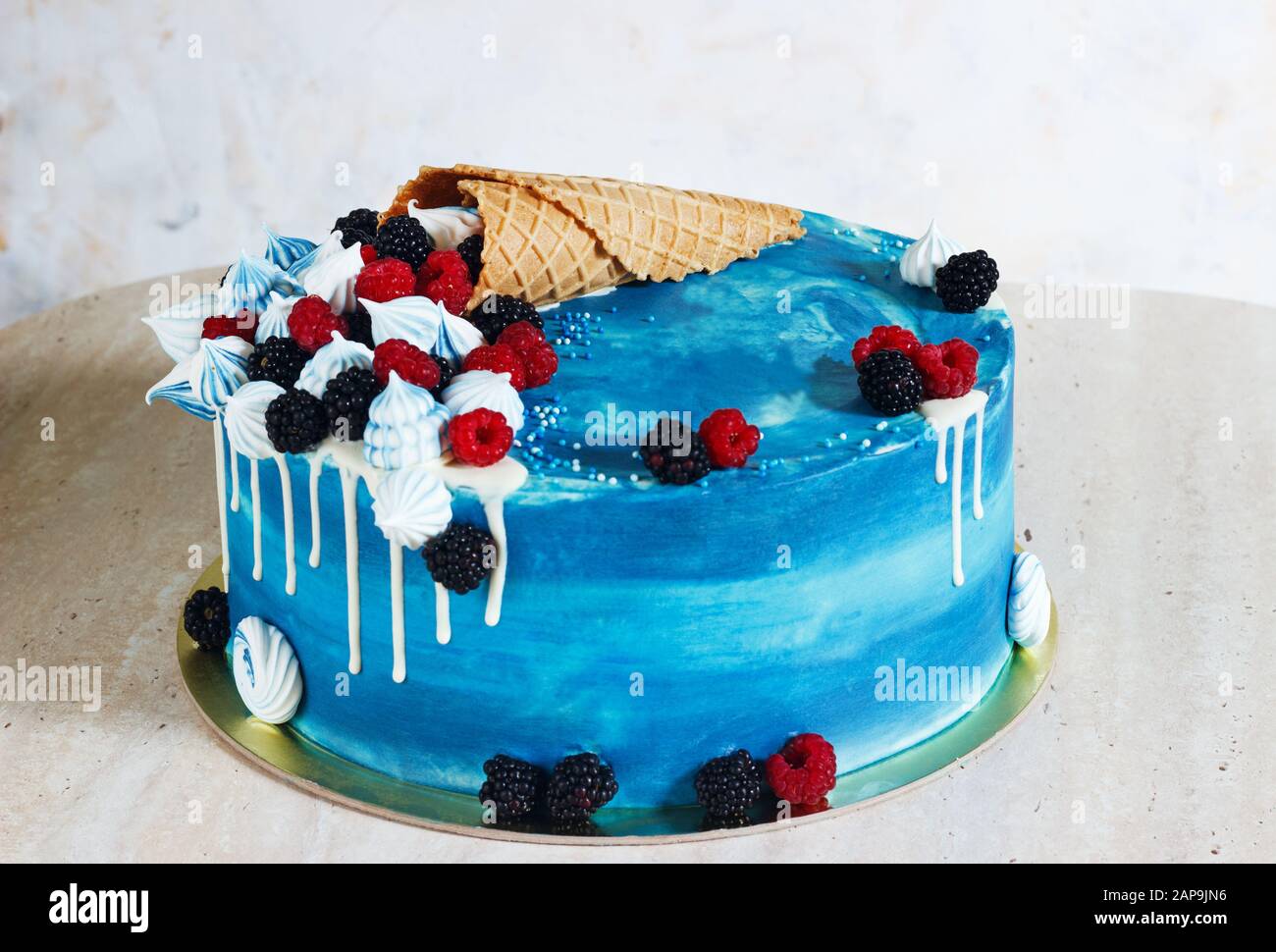 Festlicher blauer Kuchen mit Schokolade und Beeren in einem Waffelhorn. Stockfoto