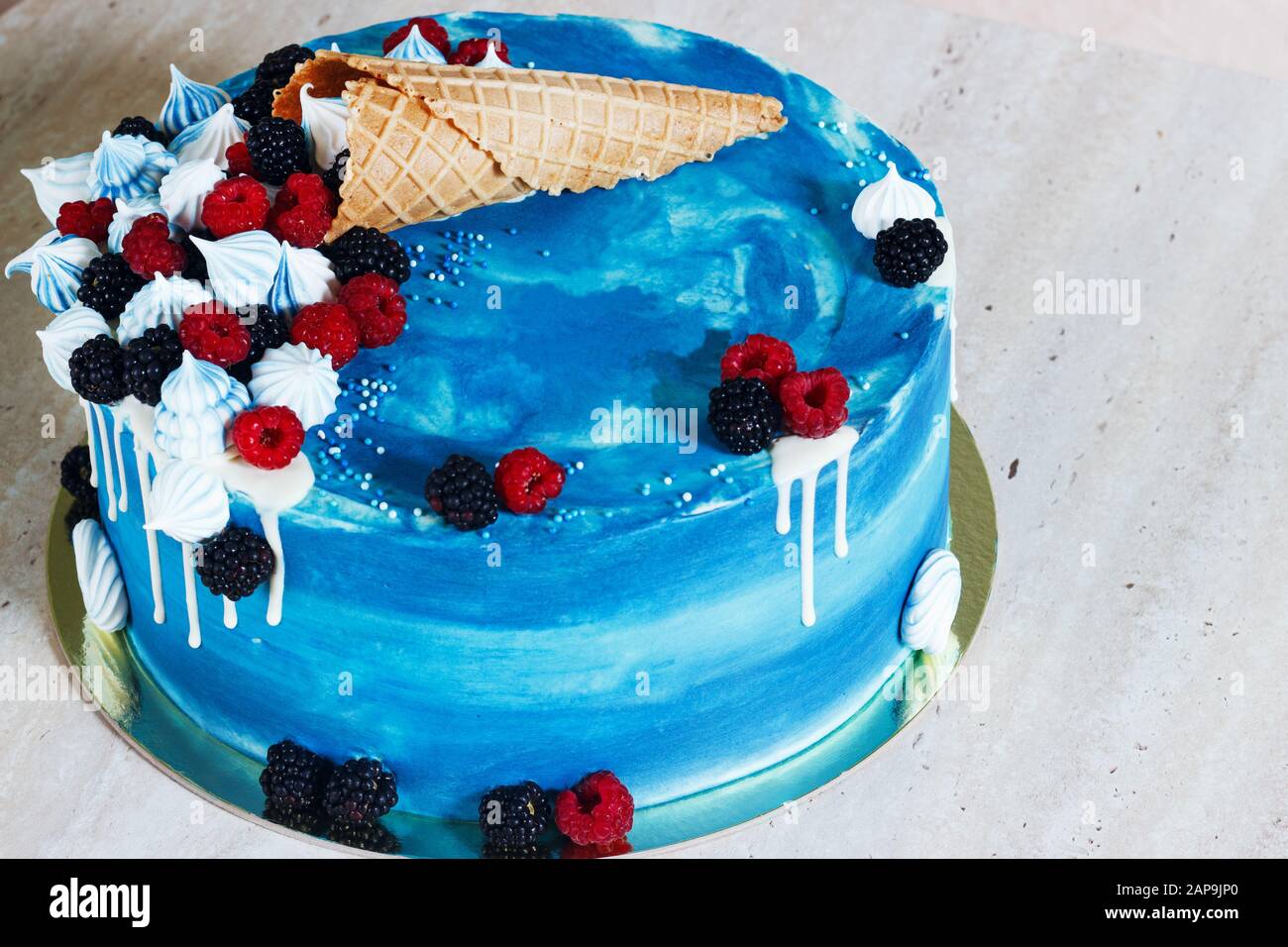 Festlicher blauer Kuchen mit Schokolade und Beeren in einem Waffelhorn Stockfoto