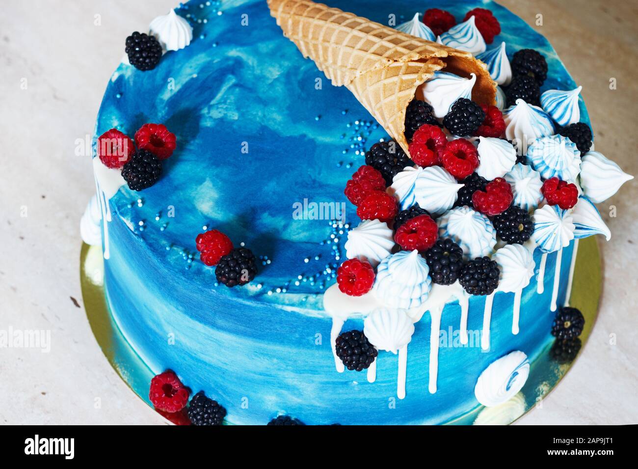 Festlicher blauer Kuchen mit Schokolade und Beeren in einem Waffelhorn Stockfoto