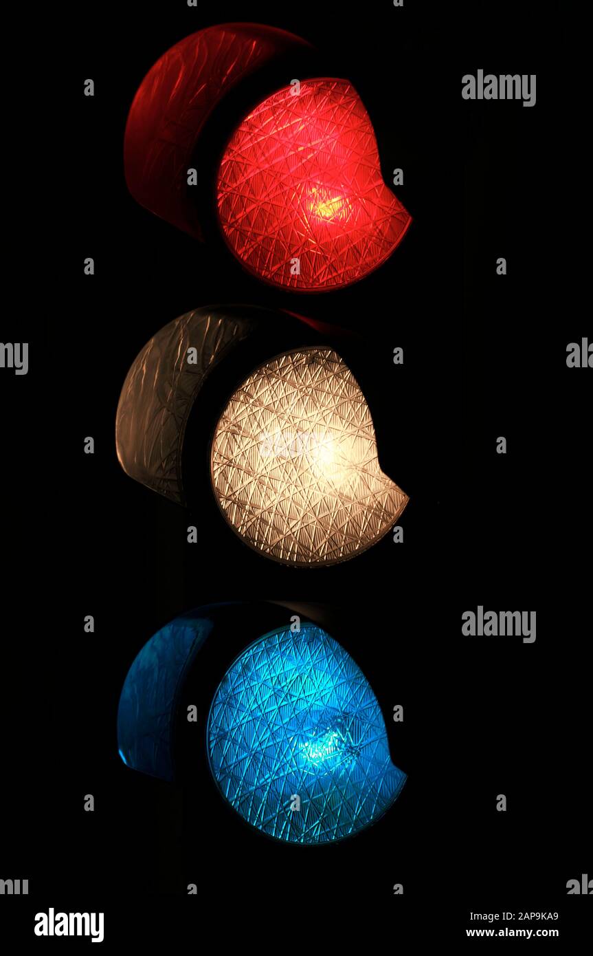 Nahverkehrsampel mit roten, weißen und blauen Lichtern, die alle vor dunklem Nachthintergrund leuchten Stockfoto