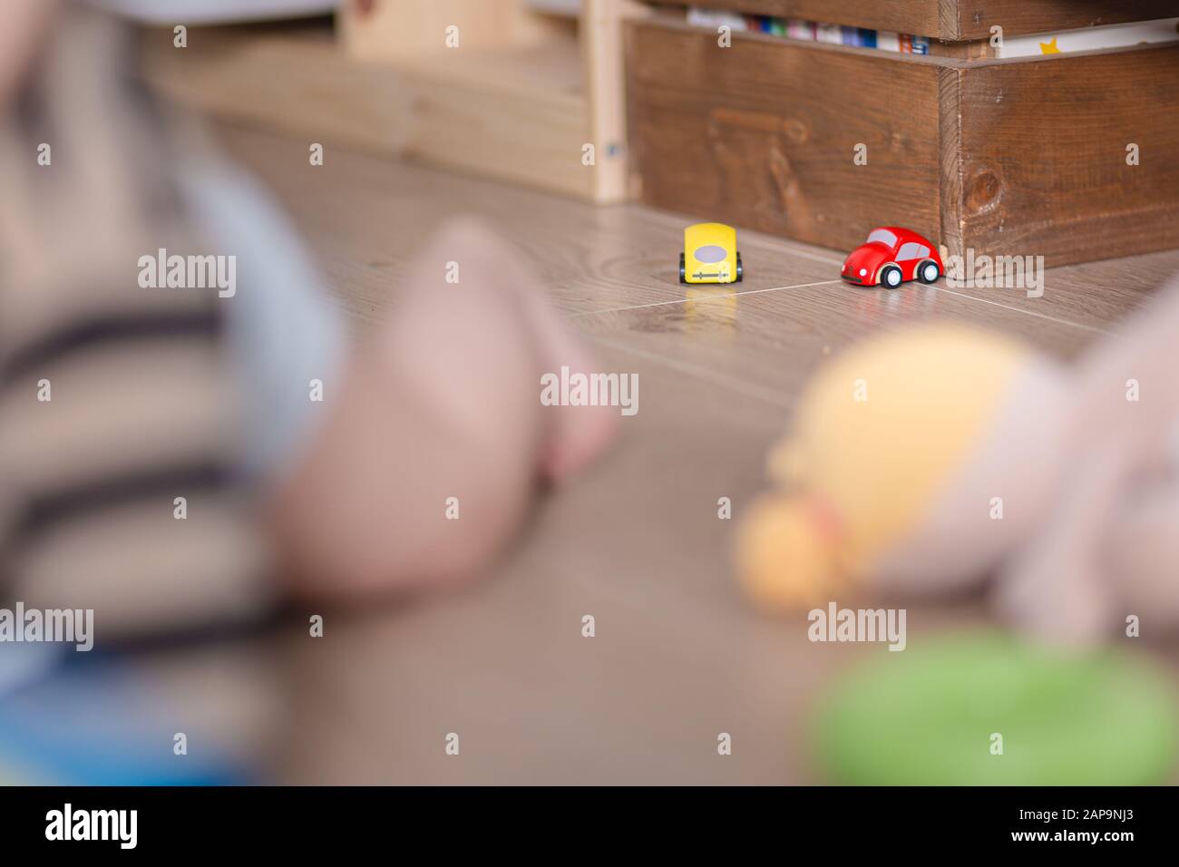Kleine Spielzeugautos auf einem Holzboden, mit dem Baby mitspielt Stockfoto