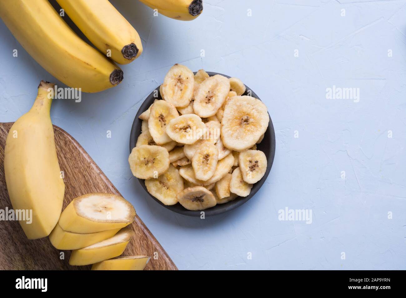 Dehydriert, frische und getrocknete Bananenchips in schwarz Schüssel auf hellen Hintergrund. Blick von oben. Stockfoto