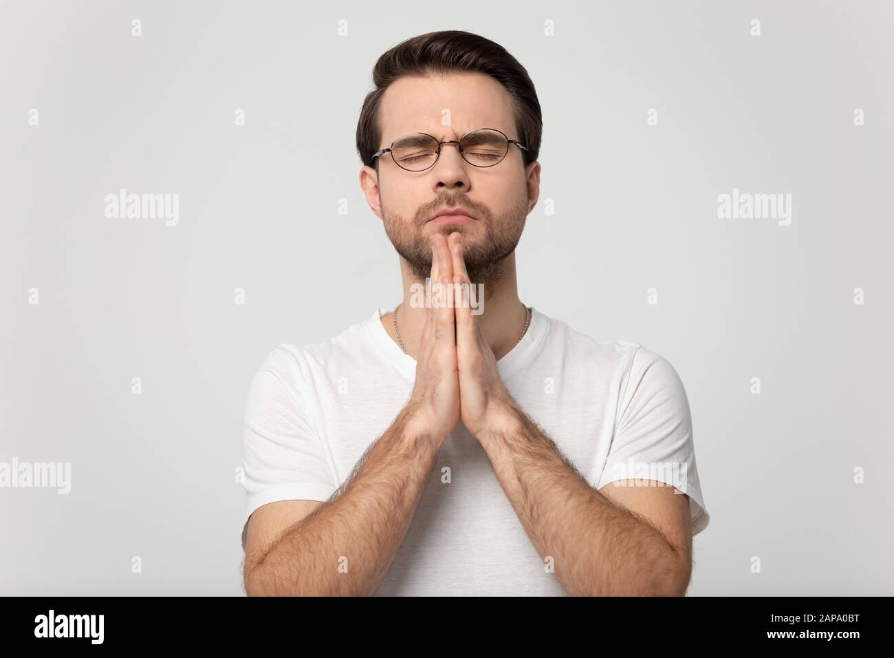 Kopf schoss betenden Mann isoliert auf grauem Studio-Hintergrundporträt. Stockfoto