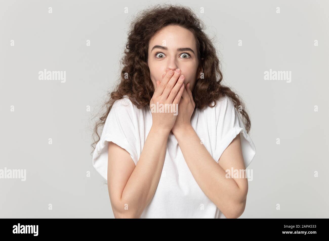 Verblüffte Frau, die den Mund mit beiden Händen bedeckt. Stockfoto