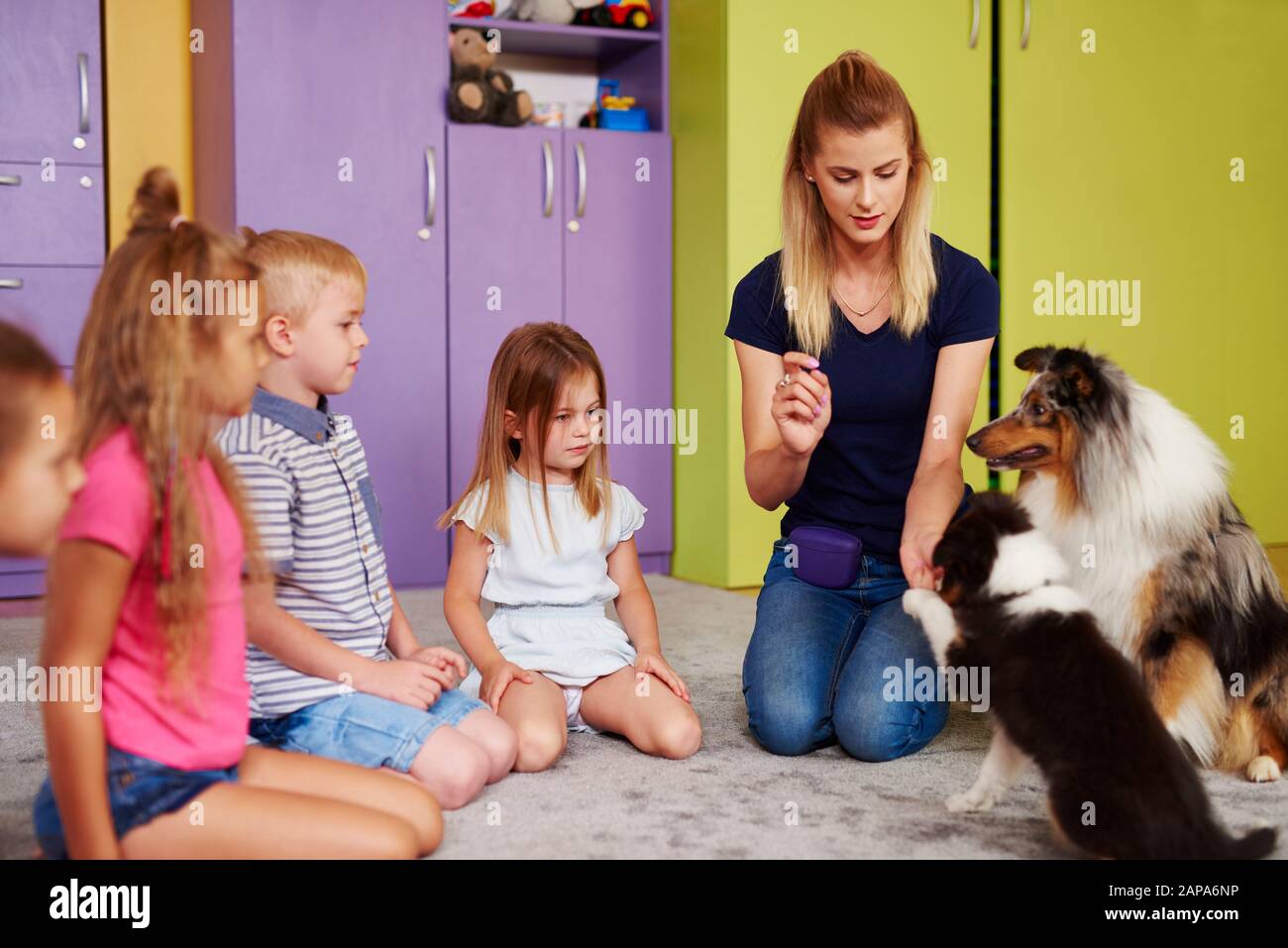 Kleine Gruppe von Kindern, die in der Vorschule mit Therapiehund spielen Stockfoto