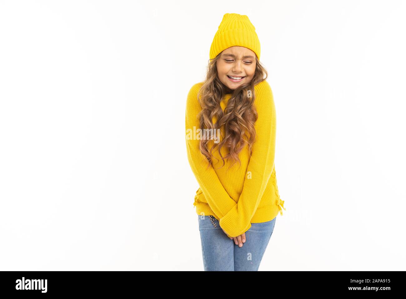 Glückliches kaukasisches Mädchen in gelbem Hut und hoody Basks isoliert auf weißem Hintergrund. Stockfoto