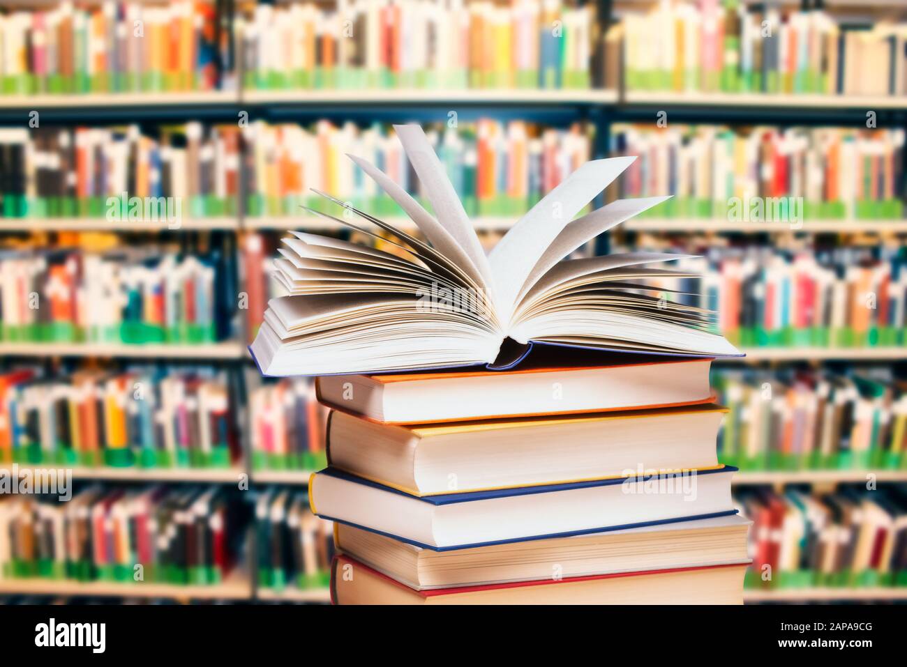 Buch auf einem Stapel vor einem großen Bücherregal geöffnet Stockfoto