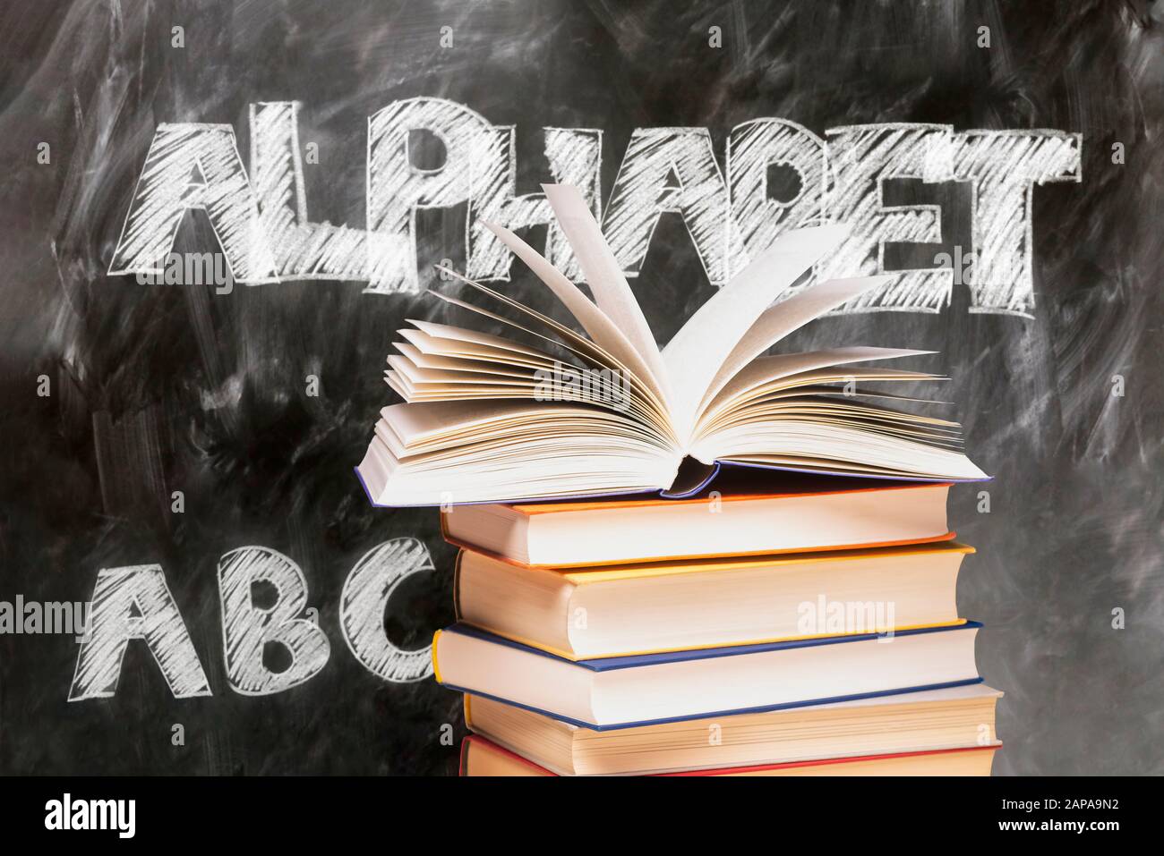 Buch auf einem Stapel vor einer Tafel mit den Wörtern Alphabet und ABC geöffnet Stockfoto