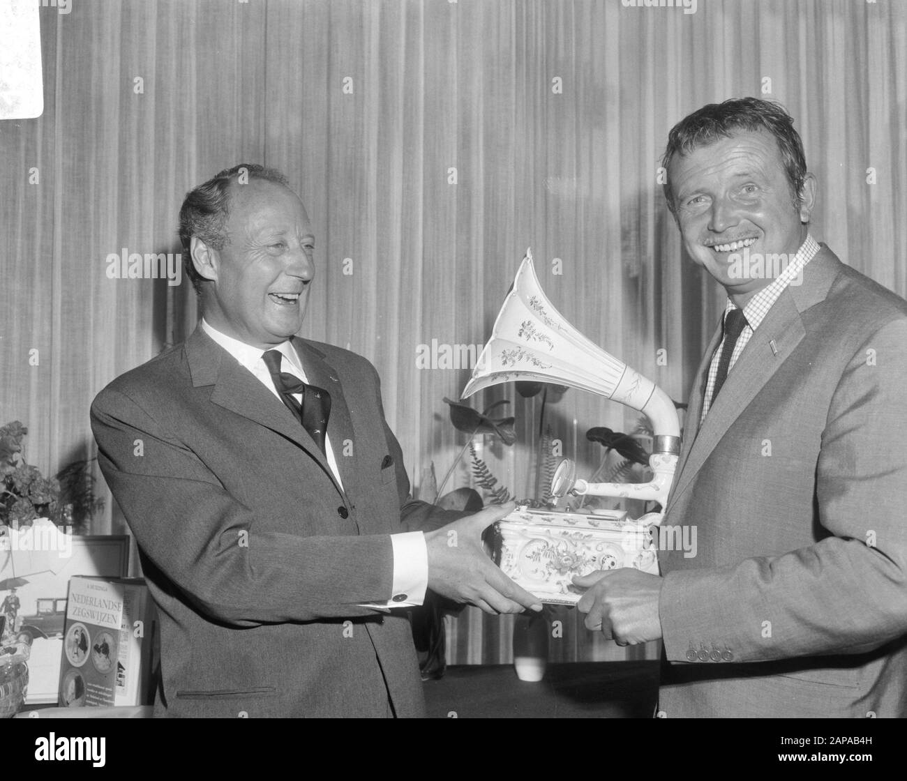 Empfang nach dem 20-jährigen Jubiläum der Grammophon-Plattenfirma N.V. Bovema im Hilton-Hotel in Amsterdam Beschreibung: Herr G.M. van Oord (Dir Bovema (l) zeigt Toon Hermans ein seltenes Porzellangramophon Datum: 19. September 1966 Ort: Amsterdam, Noord-Holland Schlüsselwörter: Künstler, Comedians, Grammophone Plattenfirmen, Empfänge persönlicher Name: Hermans, Toon, Oord, G.M. van Stockfoto