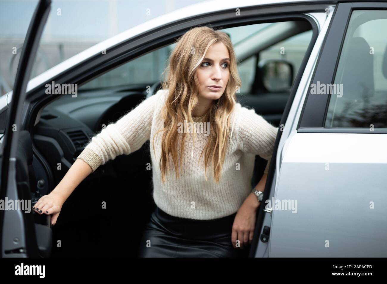 Schöne blonde Frau im Lederrock aus dem Auto Stockfotografie - Alamy