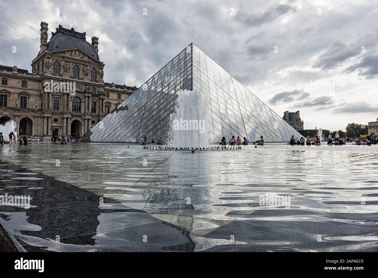 Leute, die an den Springbrunnen vor dem Louvre sitzen Stockfoto