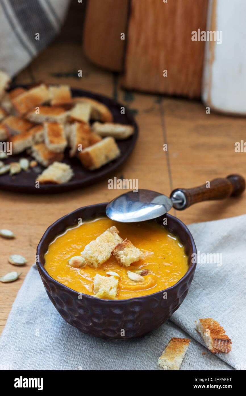 Gemüsesuppenpüree aus Kürbis, Karotten und Sellerie, serviert mit Croutons und Kürbiskernen. Rustikaler Stil. Stockfoto