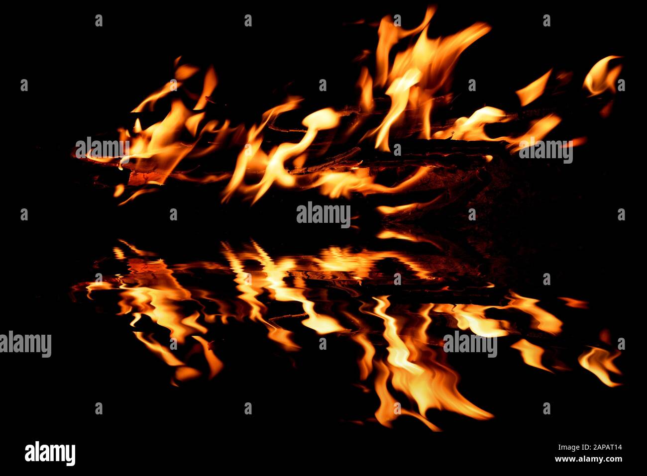 Schöne helle Flamme aus einem Feuer auf schwarzem Hintergrund mit Spiegelung im Wasser Stockfoto