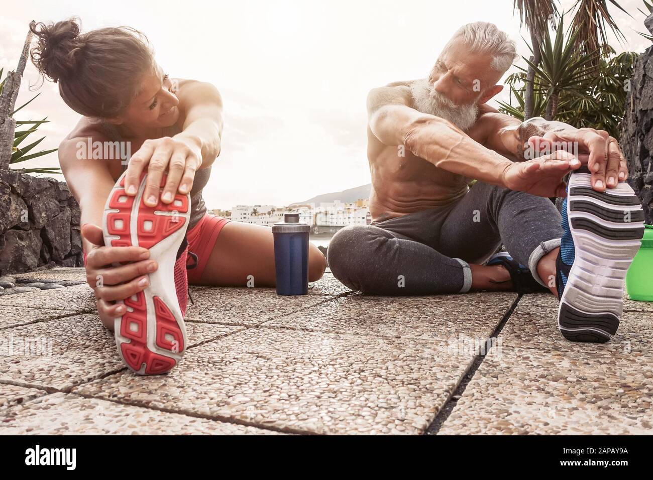 Fitness-Paar, das Dehnübungen im Freien macht - Glückliche Athleten machen eine Trainingseinheit bei Sonnenuntergang draußen Stockfoto