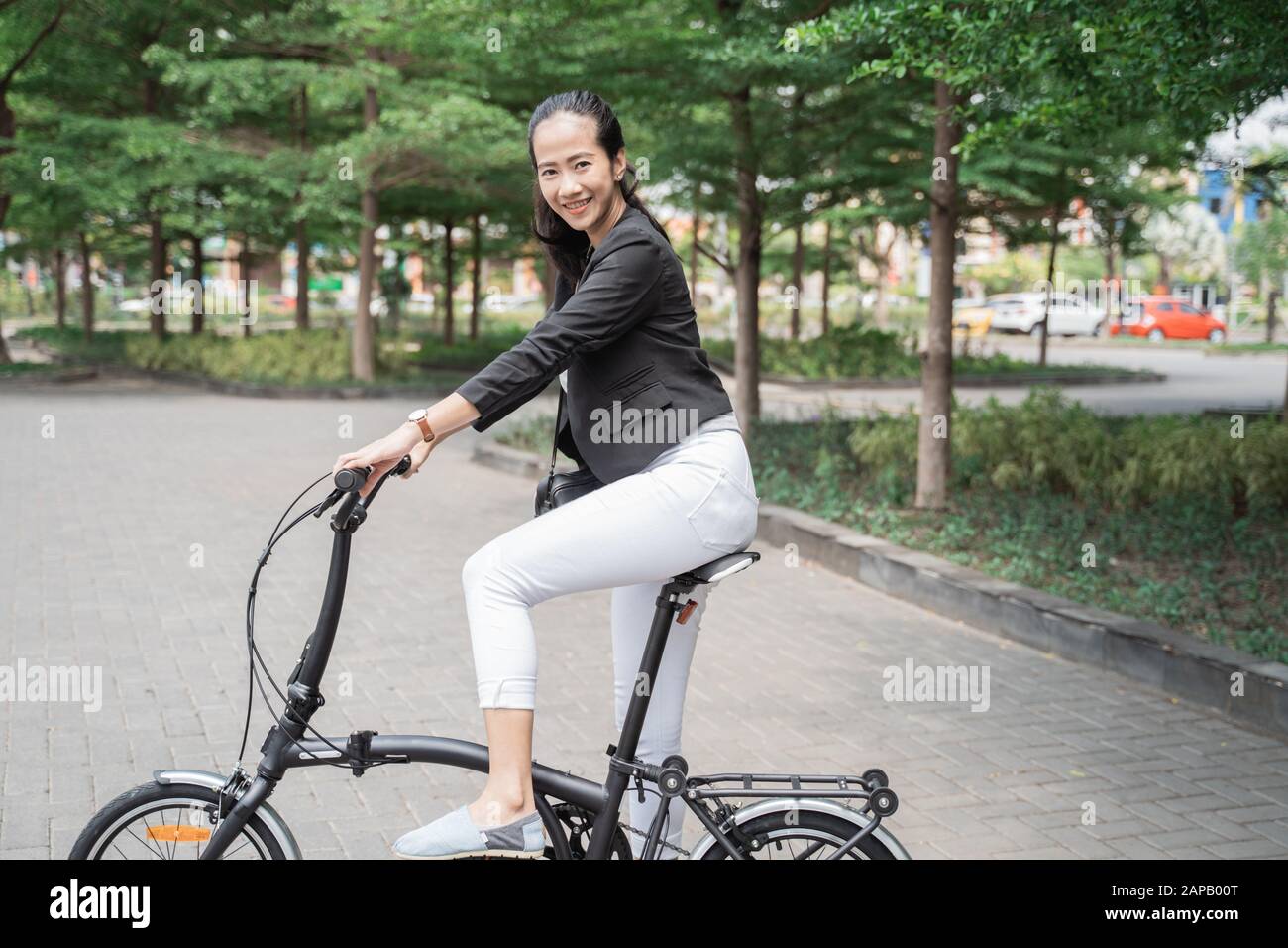 Lächelnde Geschäftsfrau, die mit ihrem Klapprad fährt Stockfoto