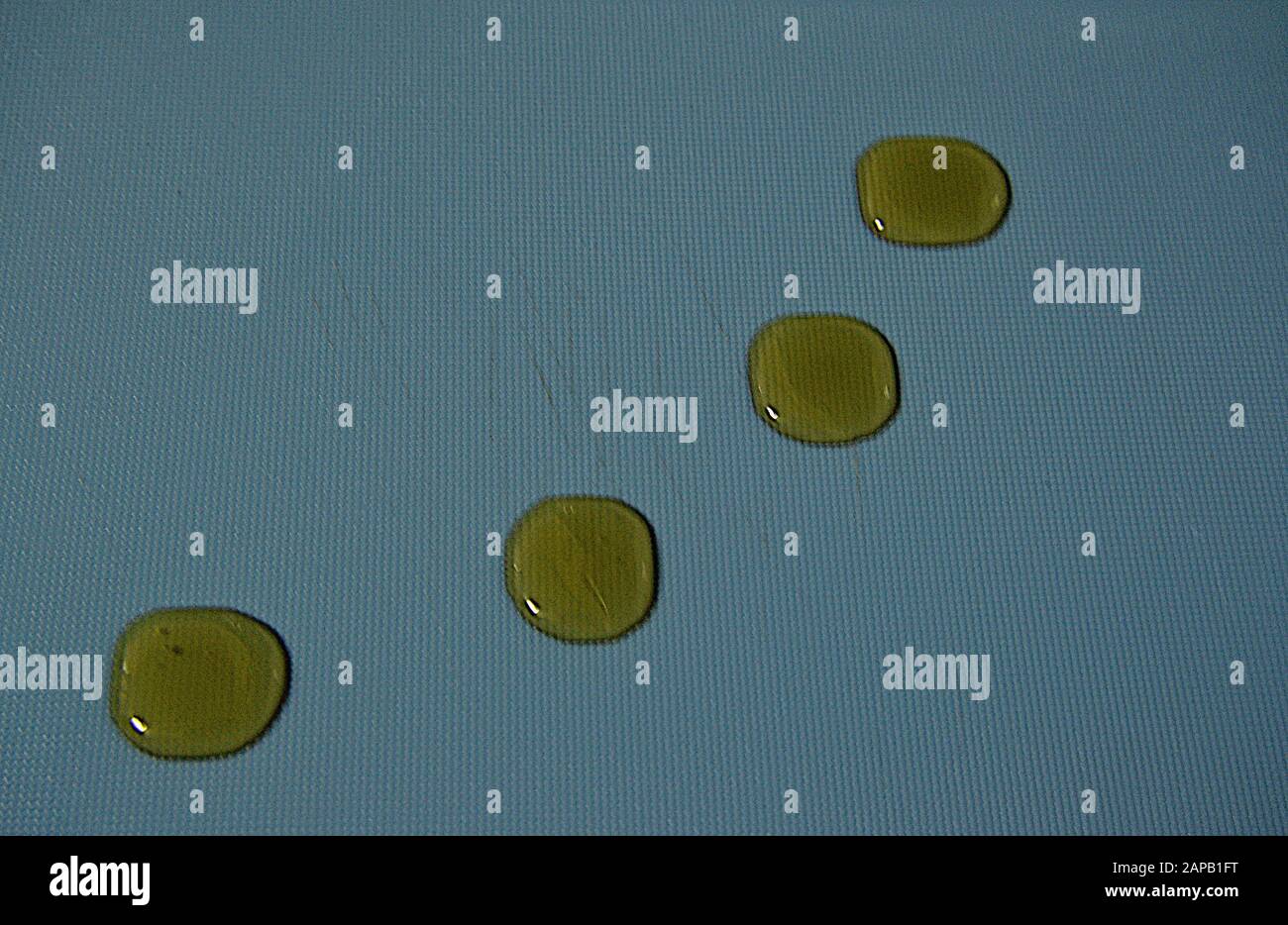 Vier Öltropfen, die einen blauen Hintergrund schmücken Stockfoto