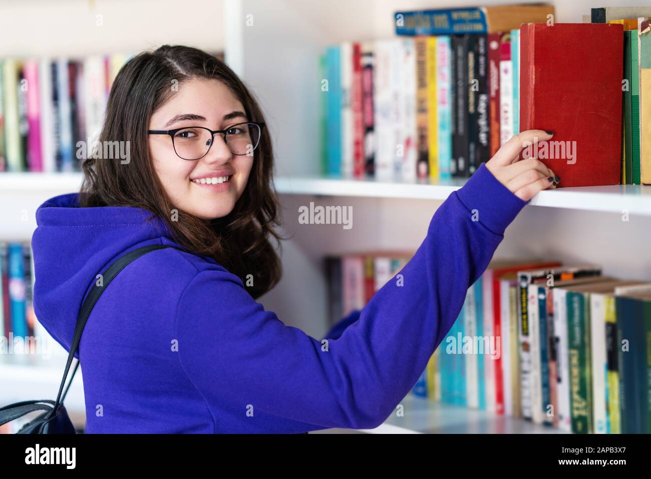 Intellektuelles Teenager-Mädchen wählt Bücher aus und wählt sie aus einer Bibliothek oder einem Buchladen Stockfoto