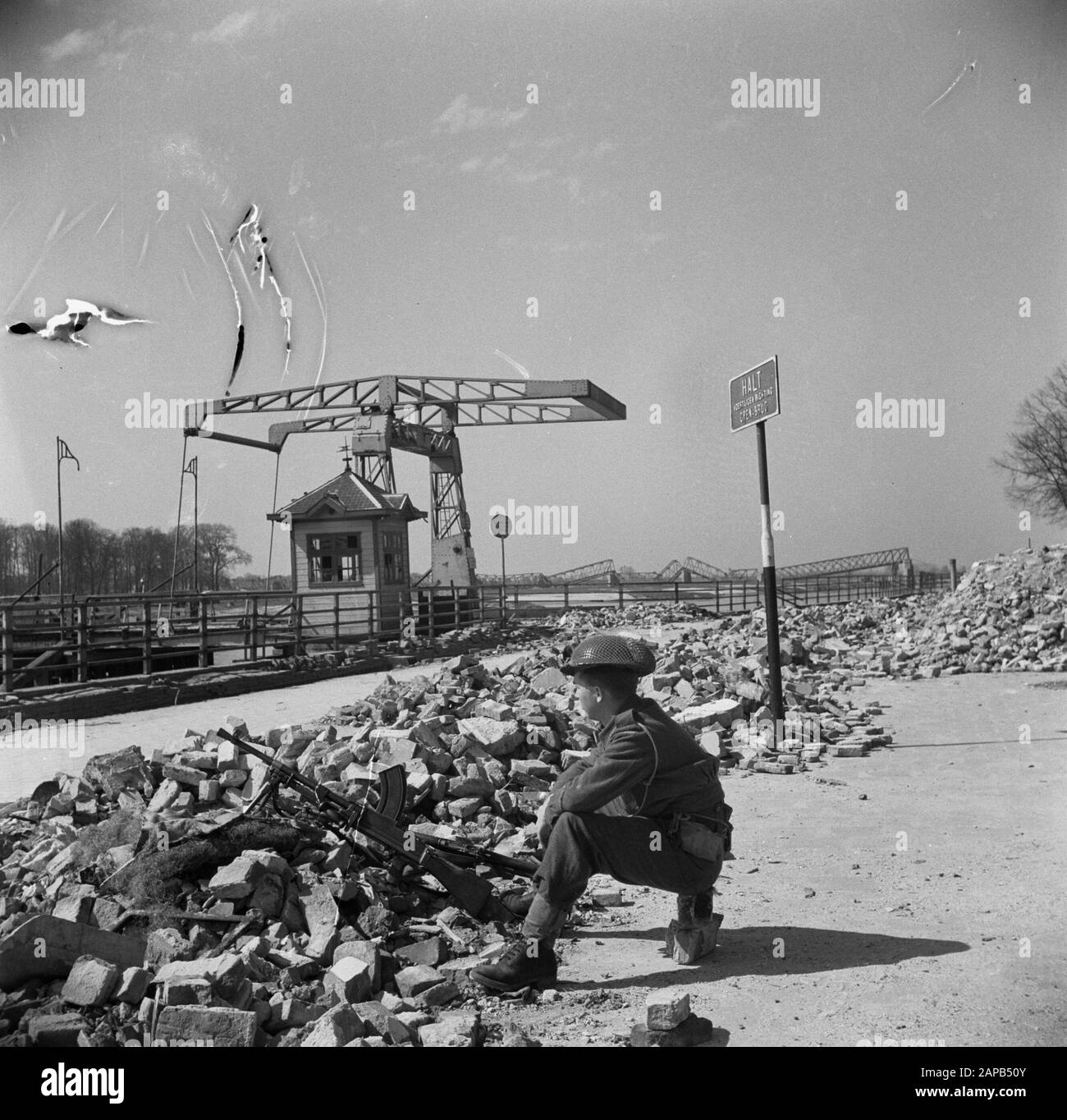Front North-East Niederlande: Deventer Beschreibung: Auf der IJsselkade verfolgt ein kanadischer Wachmann feindliche Scharfschützen über den Fluss [im Hintergrund die zerstörte Brücke von Deventer] Datum: April 1945 Ort: Deventer, Overijssel Schlüsselwörter: Brücken, Militär Stockfoto