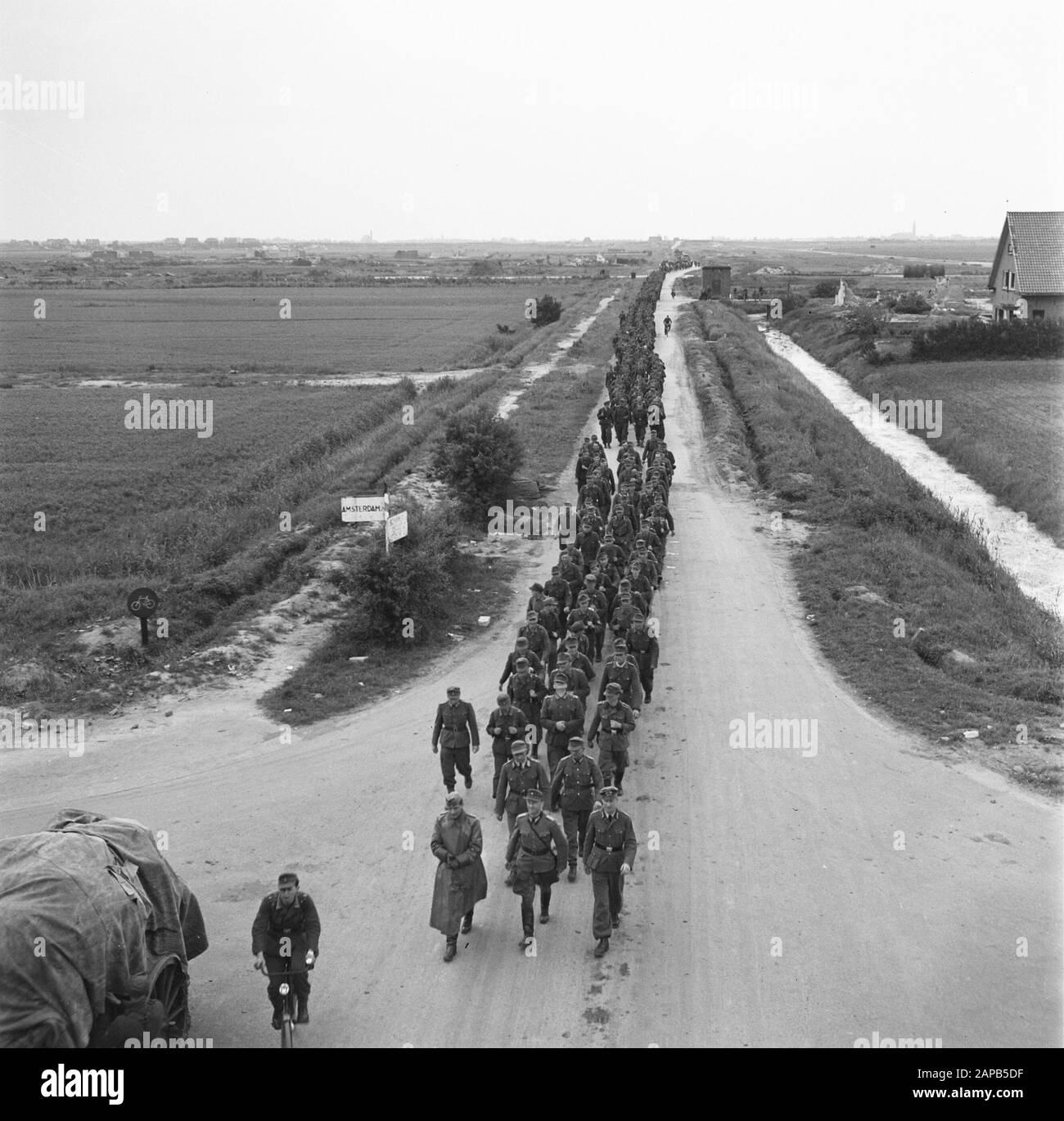 Kapitulation: Soest Beschreibung: Kolumne Deutsche auf dem Rückweg [nach der Übergabe von Waffen und Ausrüstung] Anmerkung: Foto aus hoher Position. Soldat an der Front macht mit dem Hut einen Witz. Links ein Straßenschild (links Amsterdam) Datum: 1945 Schlagwörter: Kapitulationen, Militär, Weltkrieg Stockfoto