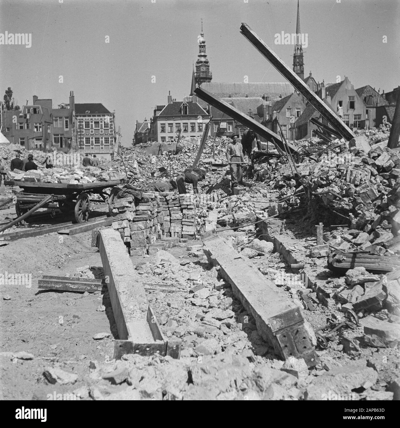 Zerstörung: Groningen Beschreibung: Die zerstörte Nordwand des Grote Marktes. Arbeiter sammeln nützliche Baumaterialien aus den Ruinen Annotation: Die abgerissenen Ruinen der historischen Nordwand des Grote Marktes - viele mittelalterlichen Ziegelsteine - lieferten das Material für die späteren Kirchenrestaurationen im Norden des Landes Datum: 1945 Ort: Groningen (Stadt) Schlüsselwörter: Arbeiter, Ziegelsteine, Kriegsschäden, Ruinen, Stadtplastiken Stockfoto