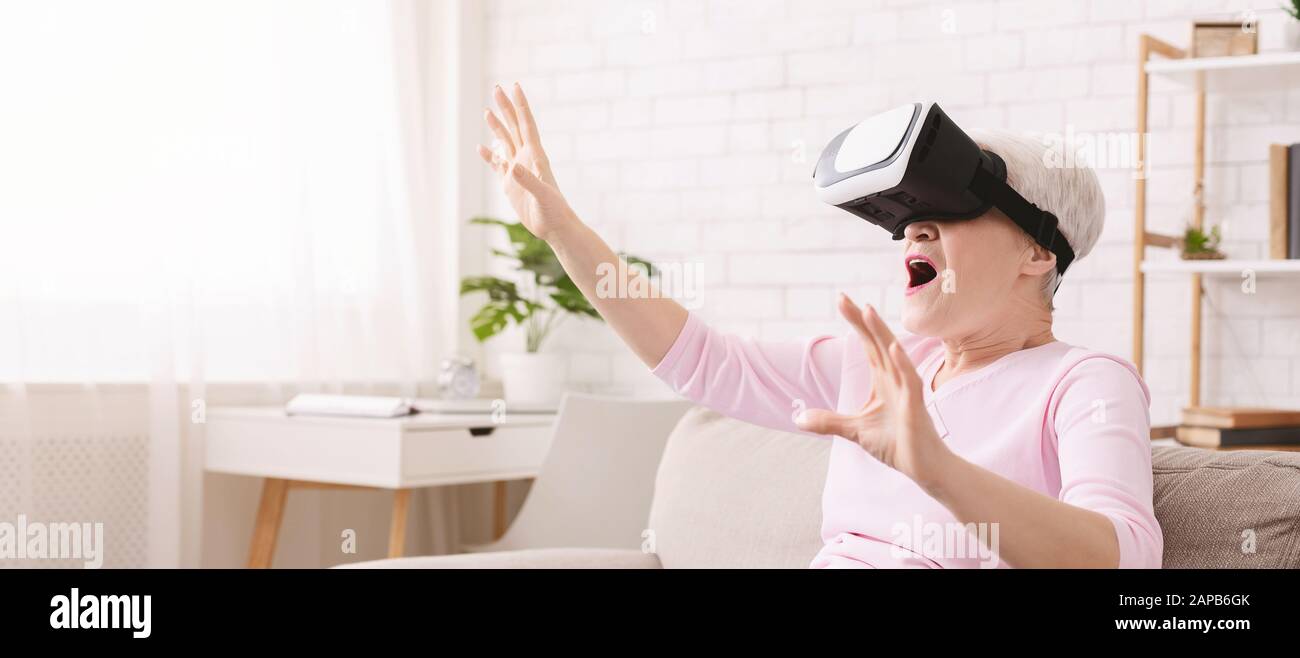 Emotional reife Dame mit VR-Headset zu Hause Stockfoto