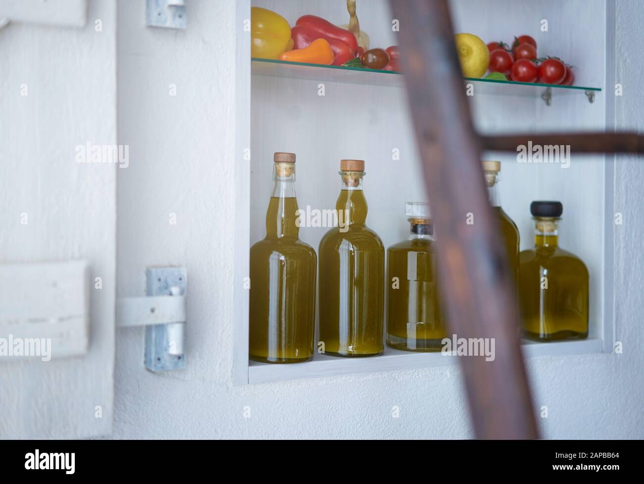 Detailreichtum aus einem Wandregal im Landhausstil Sommer in spanien.Flaschen Öl Gemüse Paprika Pfeffer Zitronentomaten verschwommen diffus Stockfoto