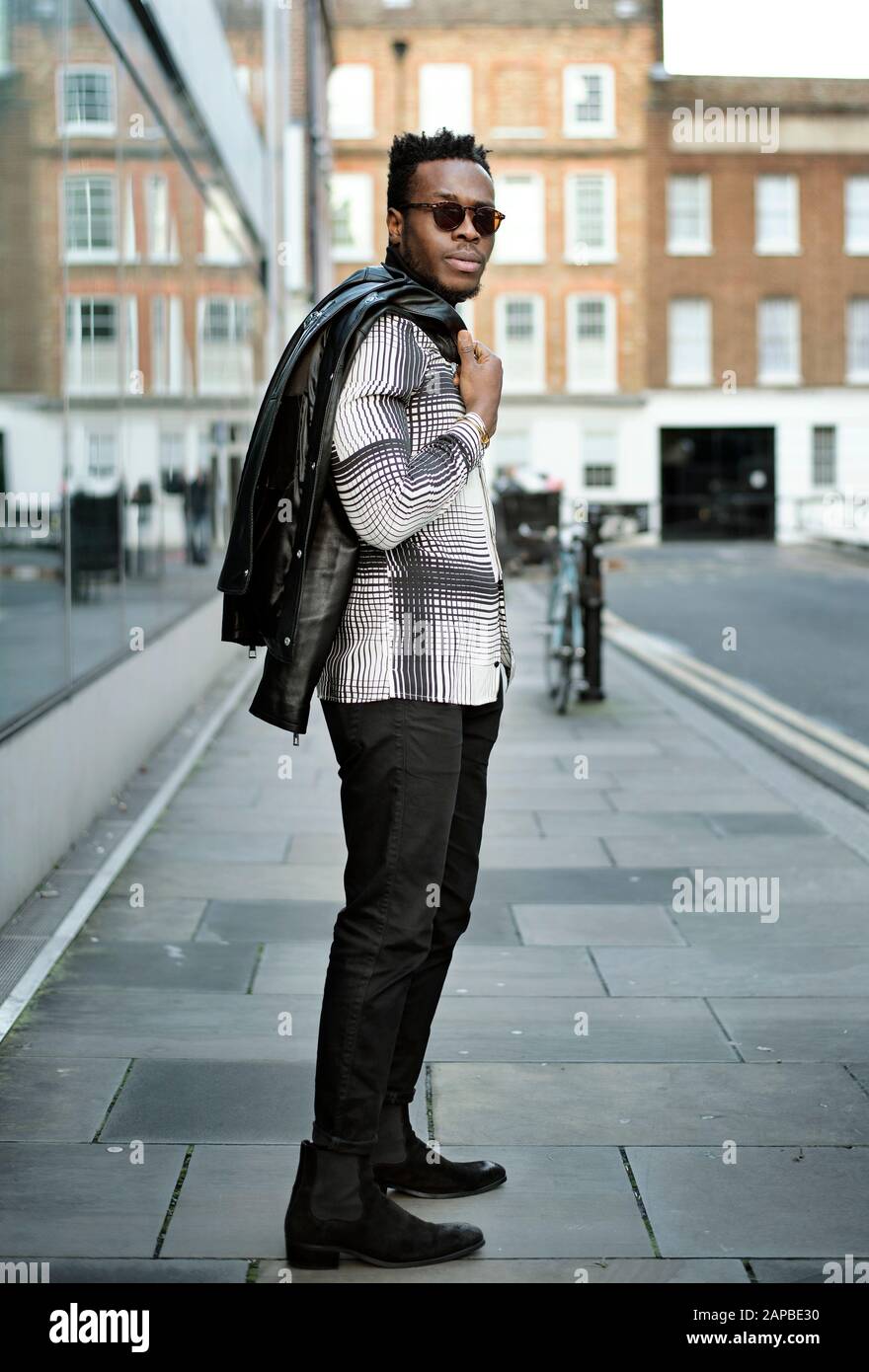 Ganzkörper-Straßenporträt von schwarzem Mann mit Sonnenbrille und eleganter Freizeitkleidung für die Kamera. Instagram Mode-Blogger schauen mit Model-Release MR Stockfoto