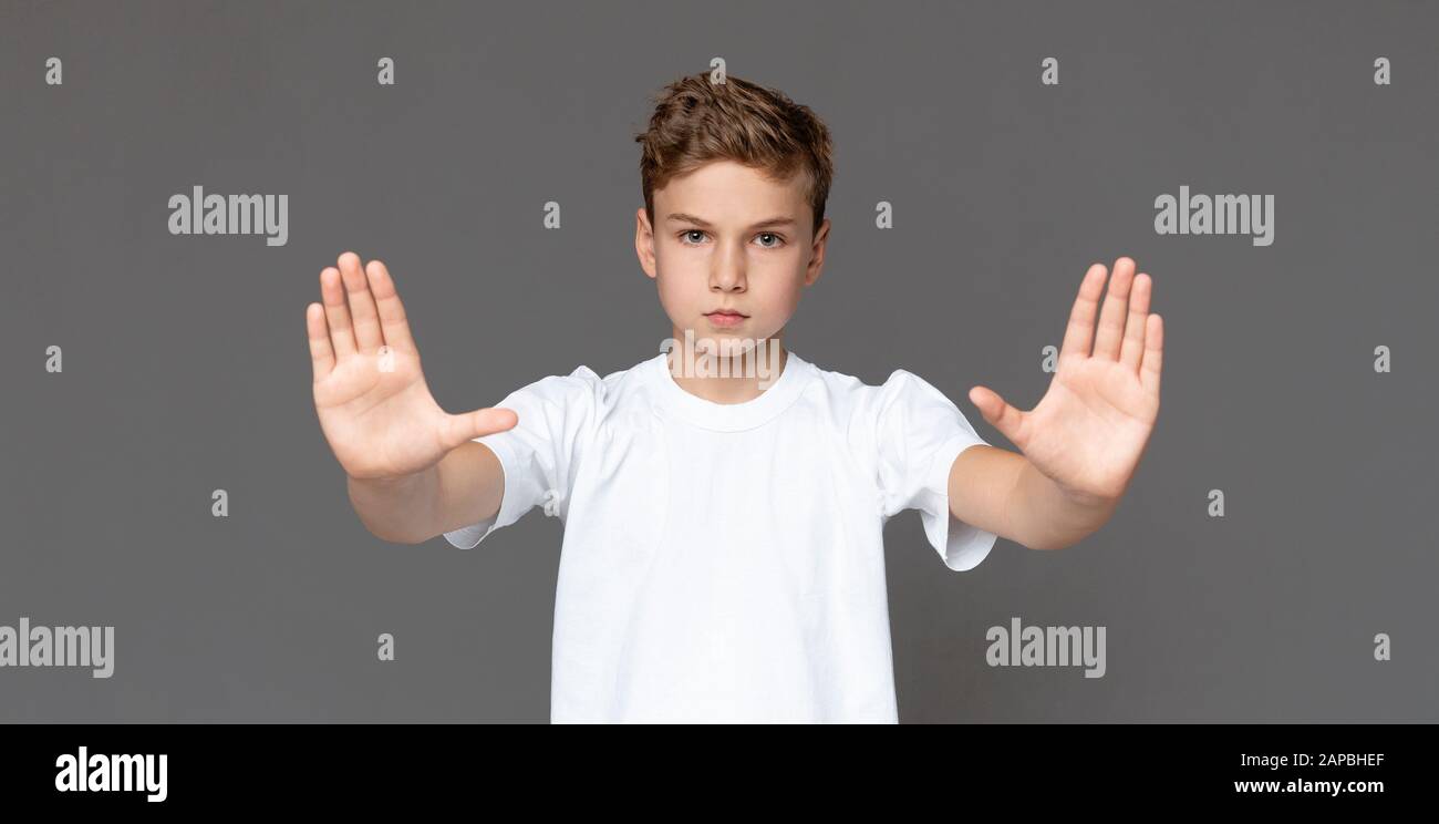 Teenager, der eine Stopp-Geste über grauem Hintergrund macht Stockfoto