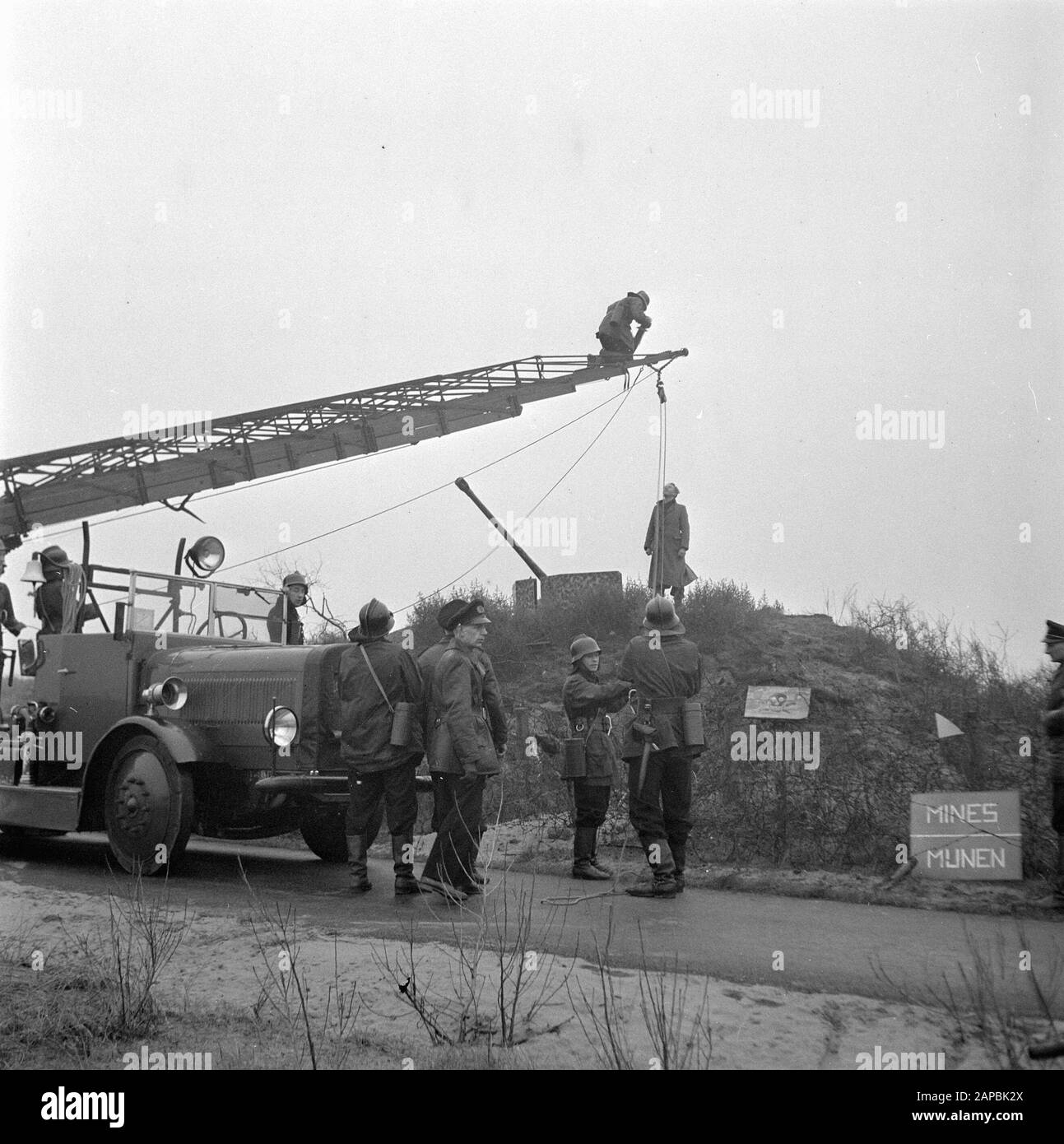 Polizei und Feuerwehr den Haag retten einen Jungen aus einem ehemaligen deutschen Bunker in einem Minenfeld. Er wurde mit Hilfe der Magirus-Autoleiter der Haager Feuerwehr gerettet Datum: 24. Dezember 1945 Ort: Den Haag, Zuid-Holland Schlüsselwörter: Feuerwehr, Sprengstoff, Kinder, Polizei, Rettungspersonname: Magirus Stockfoto