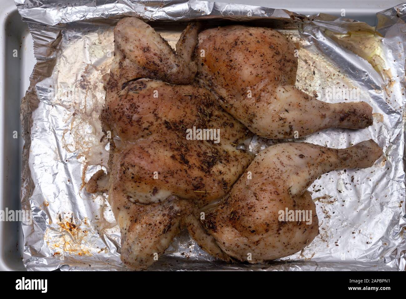 Vom Ofen gegrilltes Spatchcock Hähnchen auf Folie Stockfoto
