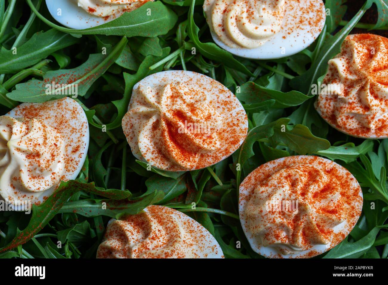 Eier mit Paprika auf frischen Nugulasalat in schwarzer ländlicher Platte auf Holztisch, gesunder vegetarischer Vorspeise oder Snack in der Nähe Stockfoto