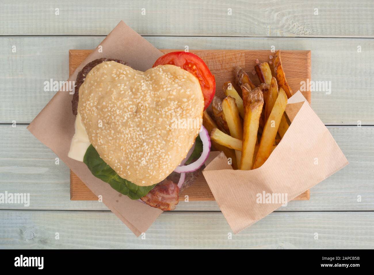 Herzförmige Hamburger und Pommes Frites, liebe Burger fast food Konzept, Valentinstag Überraschung zum Abendessen, Holz- Hintergrund, Ansicht von oben flach Stockfoto