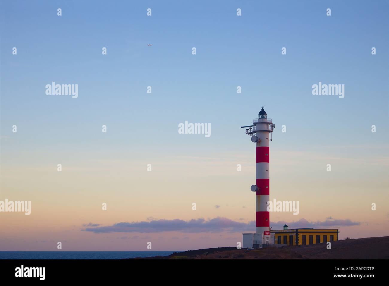 Küstenlandschaft von Teneras, in der der Leuchtturm von El Porís während des Sonnenuntergangs der Protagonist ist ist. Der blaue Himmel lässt Raum, um Texte oder Graphen hinzuzufügen Stockfoto