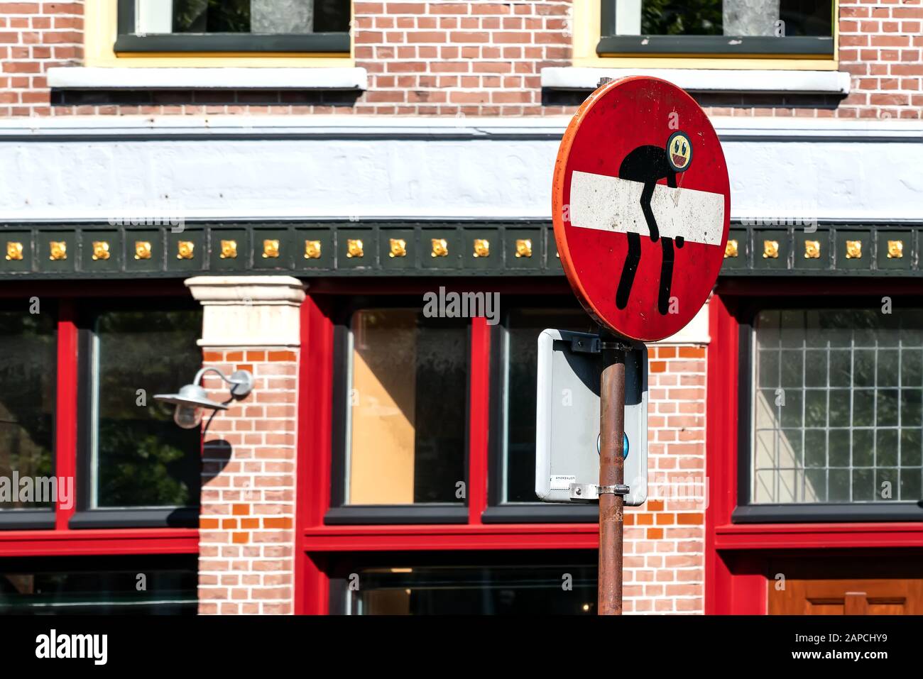 Funny Traffic Sign - Eintritt verboten - in der Stadt in Alkmaar. Ein Männchen will das Verkehrszeichen entfernen. Stockfoto