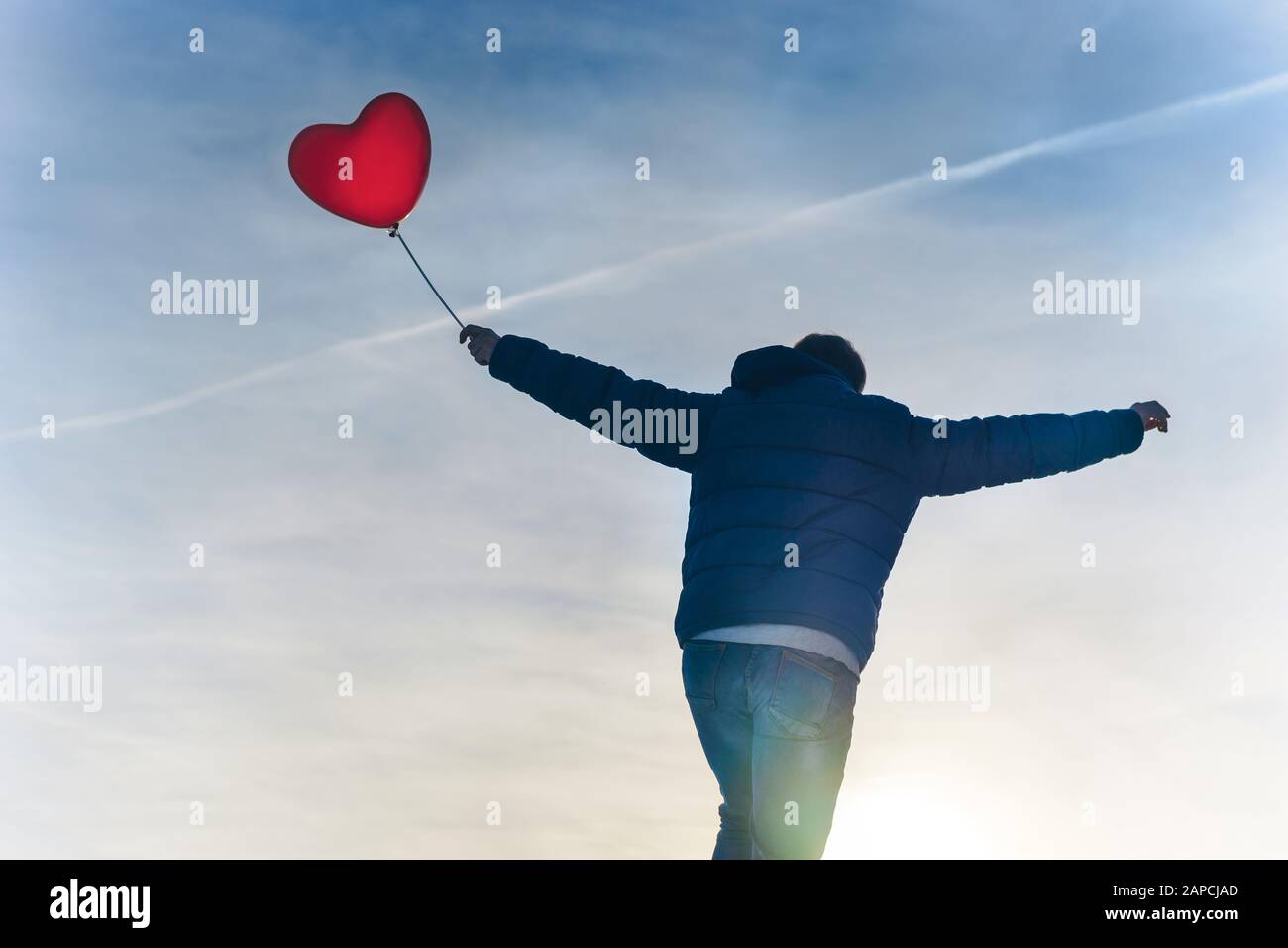 Mann von hinten mit einem roten Herzluftballon Stockfoto