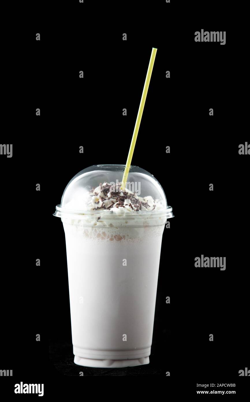 Milchshake in einem Glas mit Schokoladenstückchen. Im Glas gibt es ein Trinkhalm. Isoliert auf schwarzem Hintergrund. Stockfoto